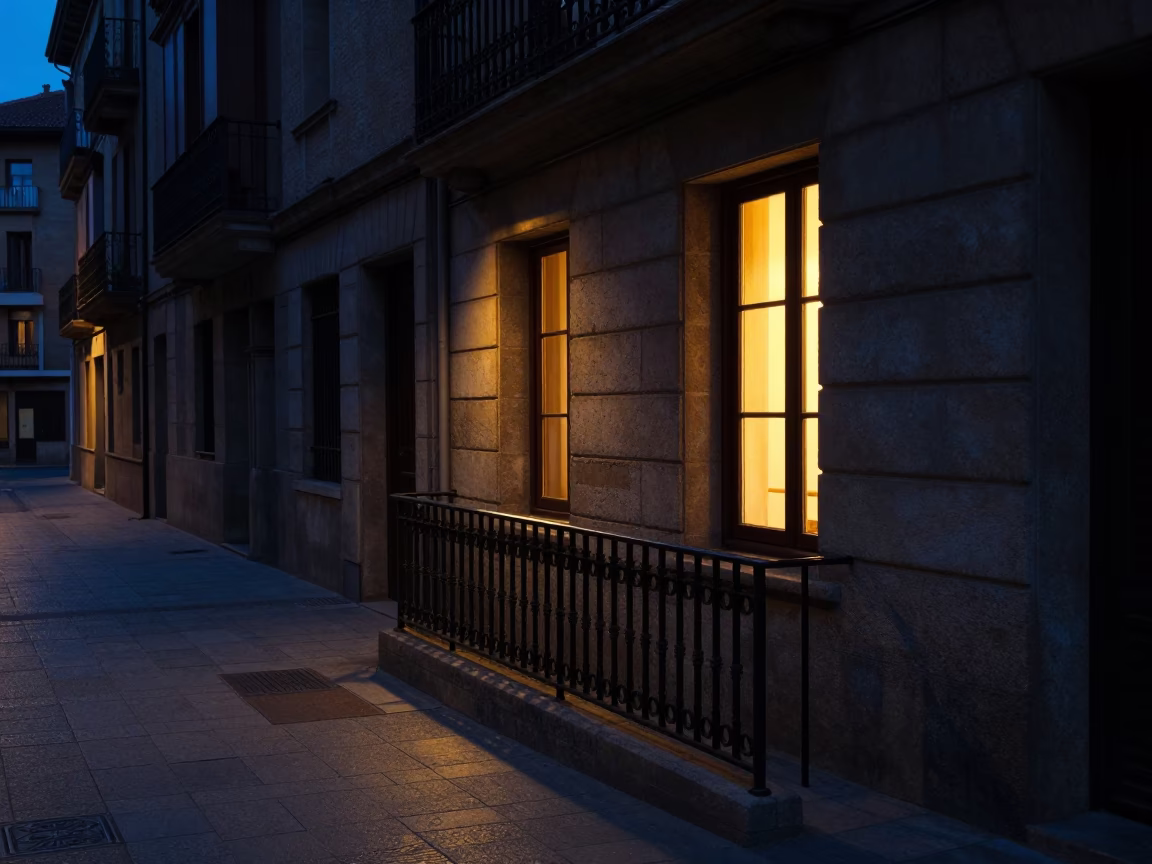Predawn Bilbao Street Scene with Window Light on Rail and Fallen Petals in in Bilbao, Spain