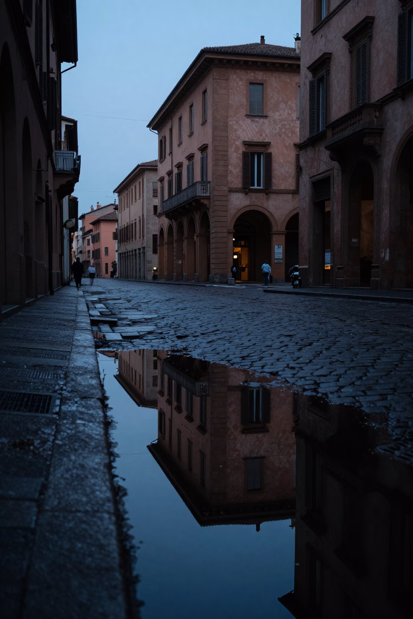Predawn Bologna Italy Street Scene with Puddle Reflections of Hotel Windows and Tail Lights in in Bologna, Italy