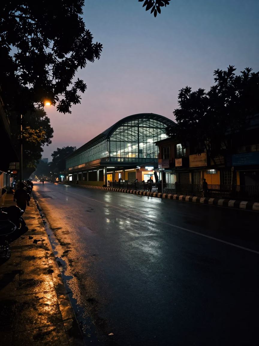 Predawn Kolkata street scene with wet asphalt and distant train station lights in in Kolkata, India