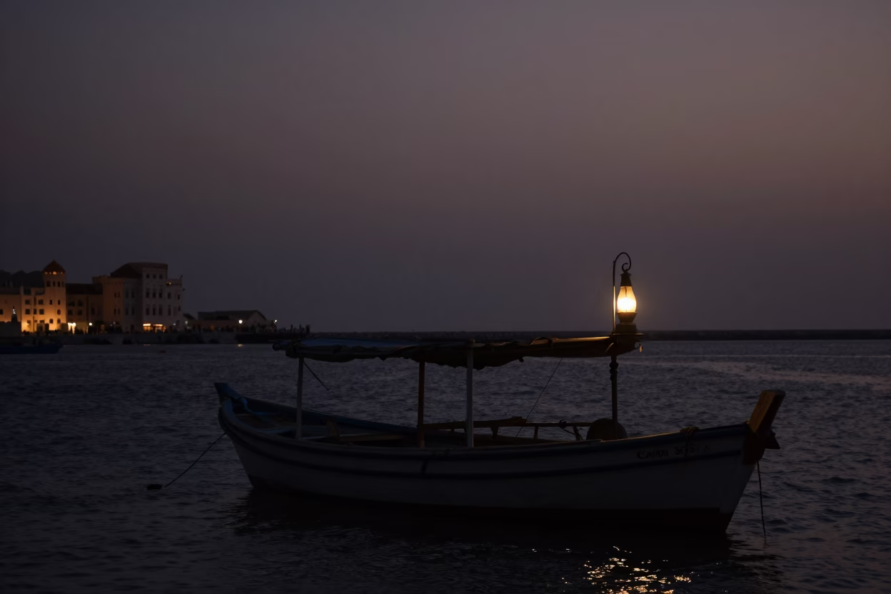 Predawn Muscat Oman Harbor with Hurricane Lamp Light and Traditional Dhow Silhouette in in Muscat, Oman