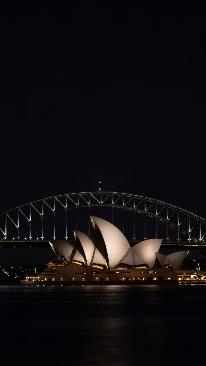 Predawn Sydney Harbour Bridge and Opera House silhouette against dark water with fishing boat in in Sydney, New South Wales, Australia