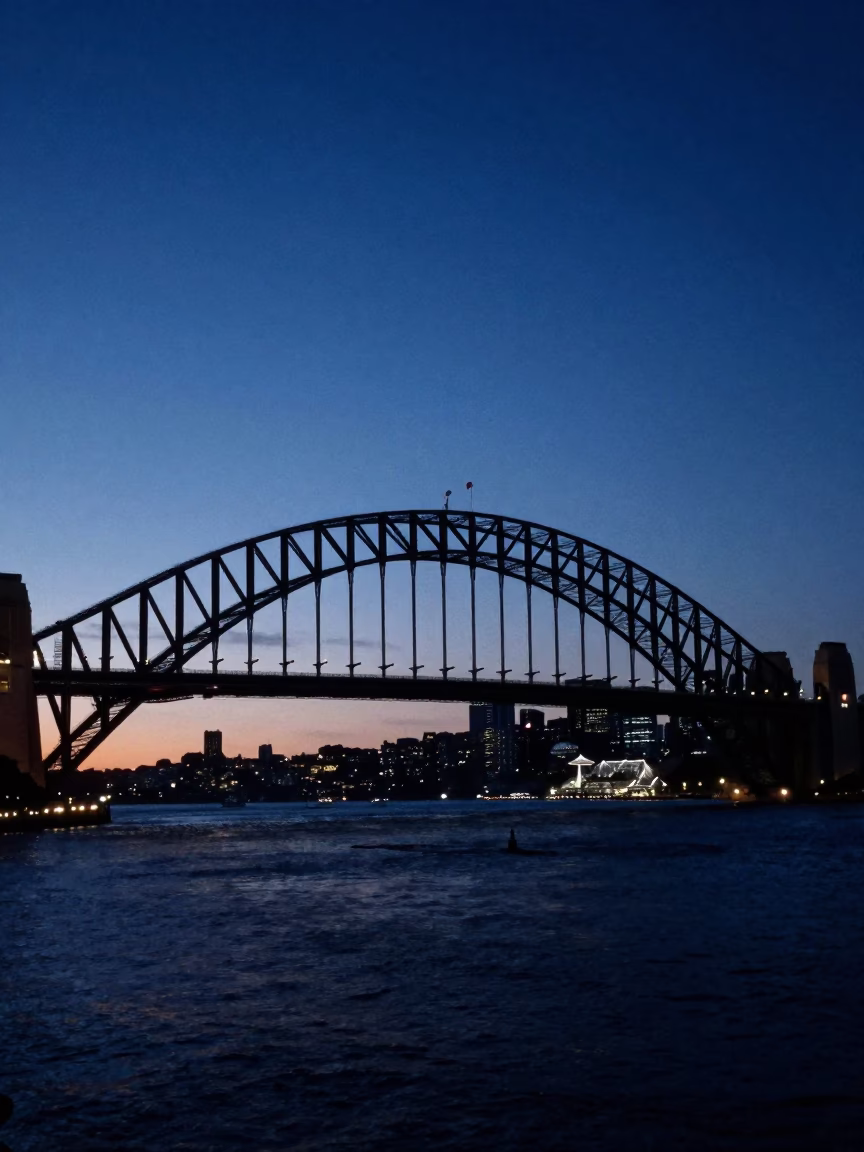 Predawn Sydney Harbour Bridge Silhouette with Harbour Water and Urban Lights in in Sydney, New South Wales, Australia