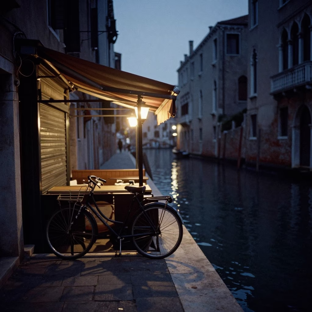 Predawn Venice Canal Scene with Bicycle Leaning Against Cafe and Demolition Dumpster in Shadows in in Venice, Italy