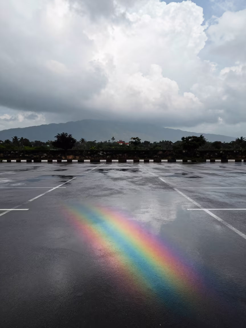 Rain Puddle Oil Slick Rainbow Gujarat in over a horizon of stacked thunderheads in Gujarat