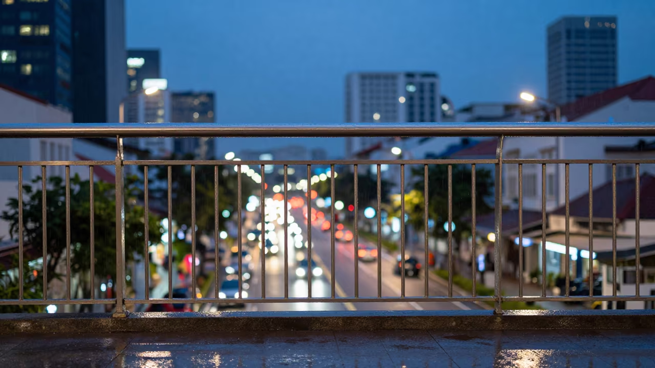 Rain Soaked Railing Glows Over Bugis City in outside a corner cafe in Bugis, Singapore