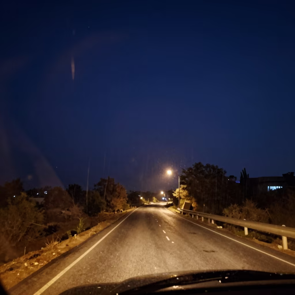 Rain streaks on car windshield night sky in along a switchback approach near Swabi