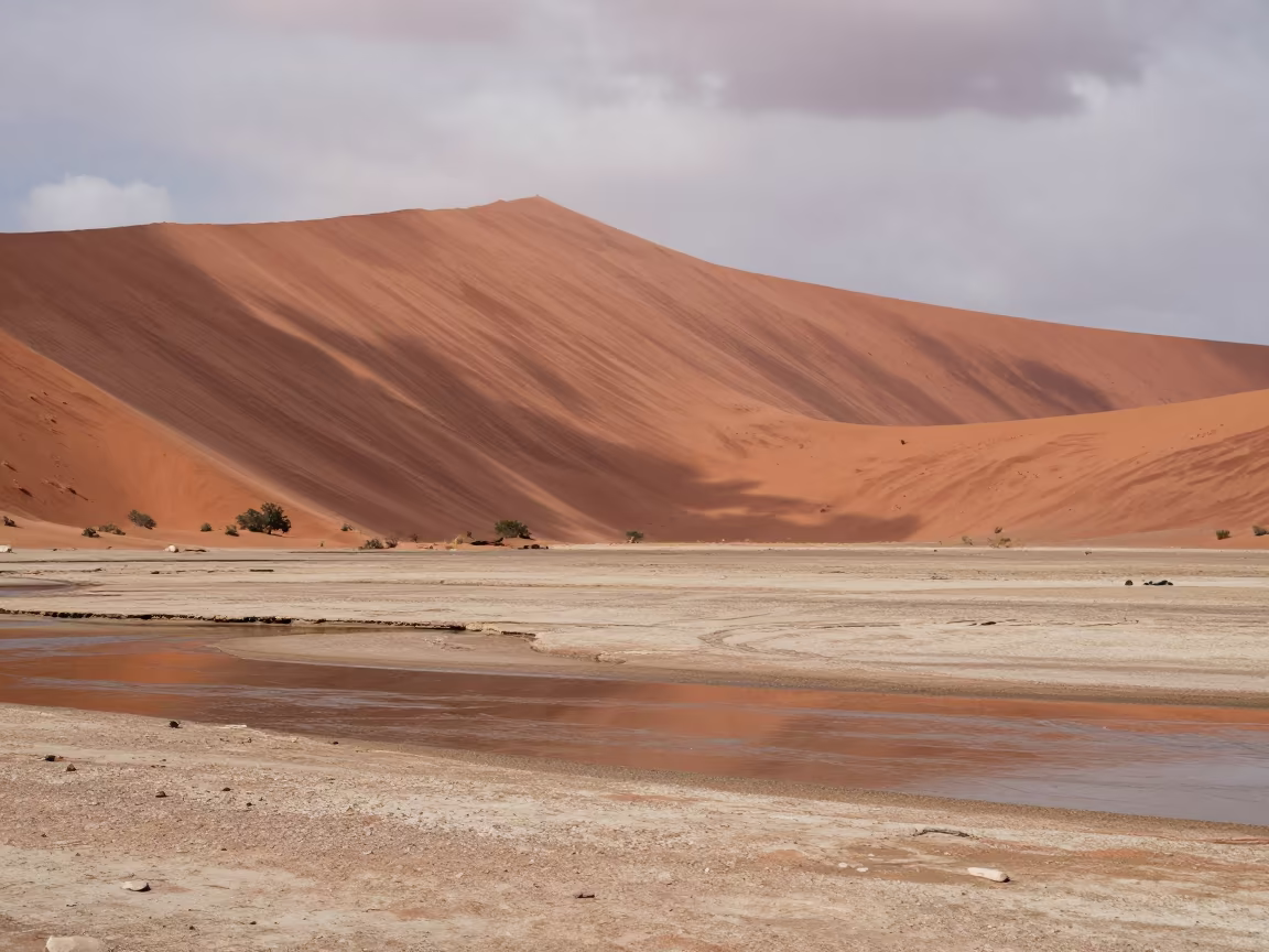 Red Dune Over Dry Riverbed Under Noon Sun in across a wide valley floor in Grenada