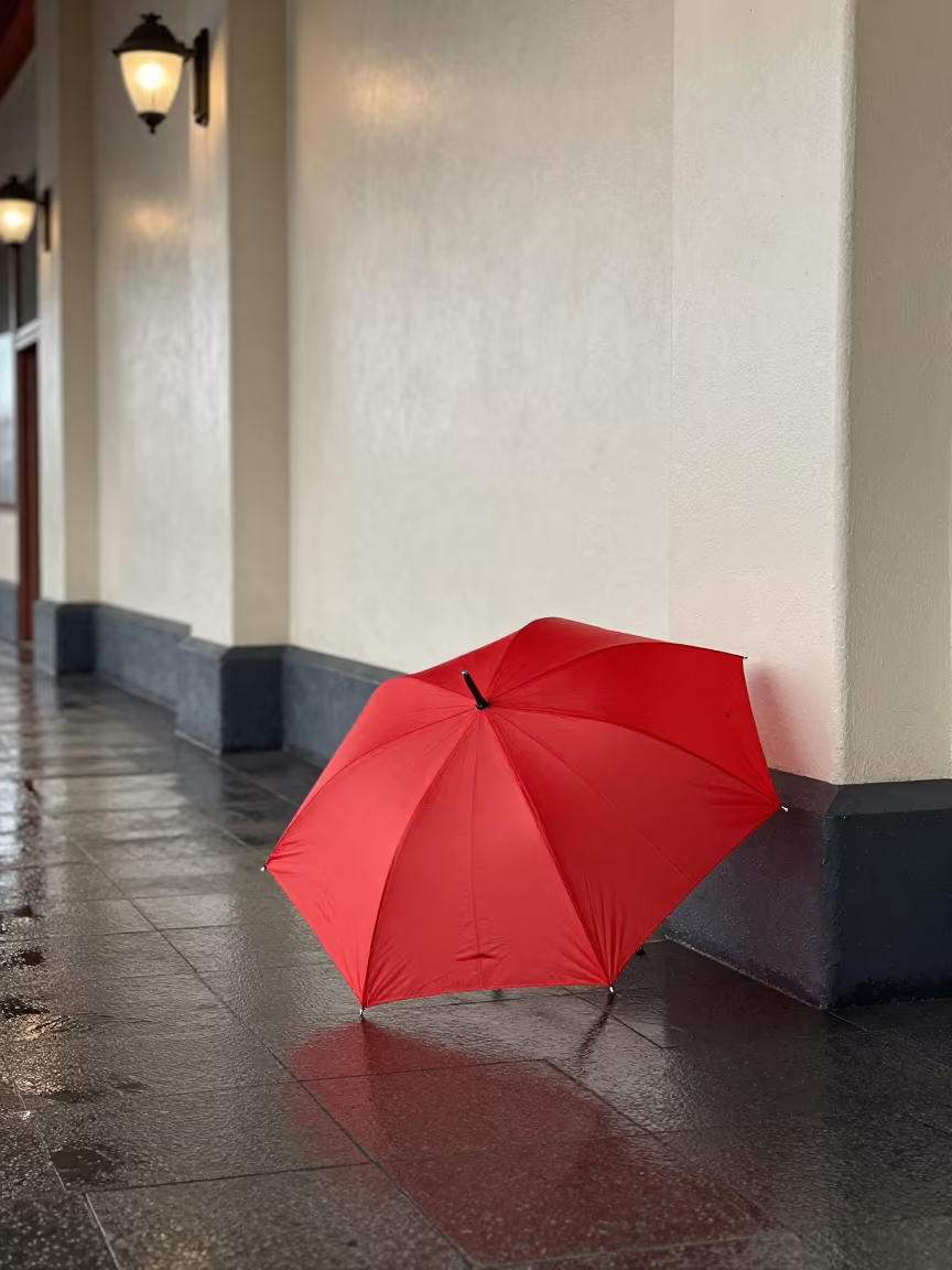 Red Umbrella on Wet Pavement in Train Terminal in inside a restored train terminal near Akure