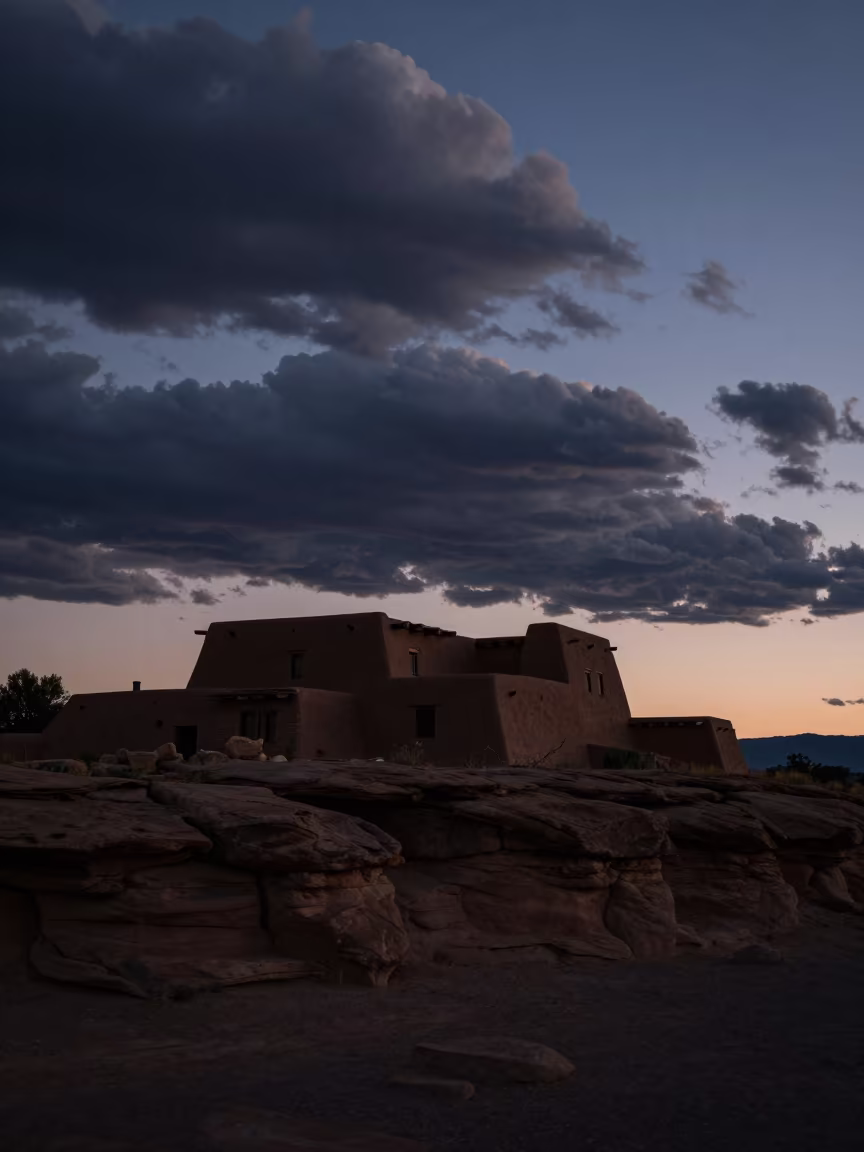 Silhouetted Adobe Pueblo Under Sandstone Cliff at Twilight in near Albuquerque