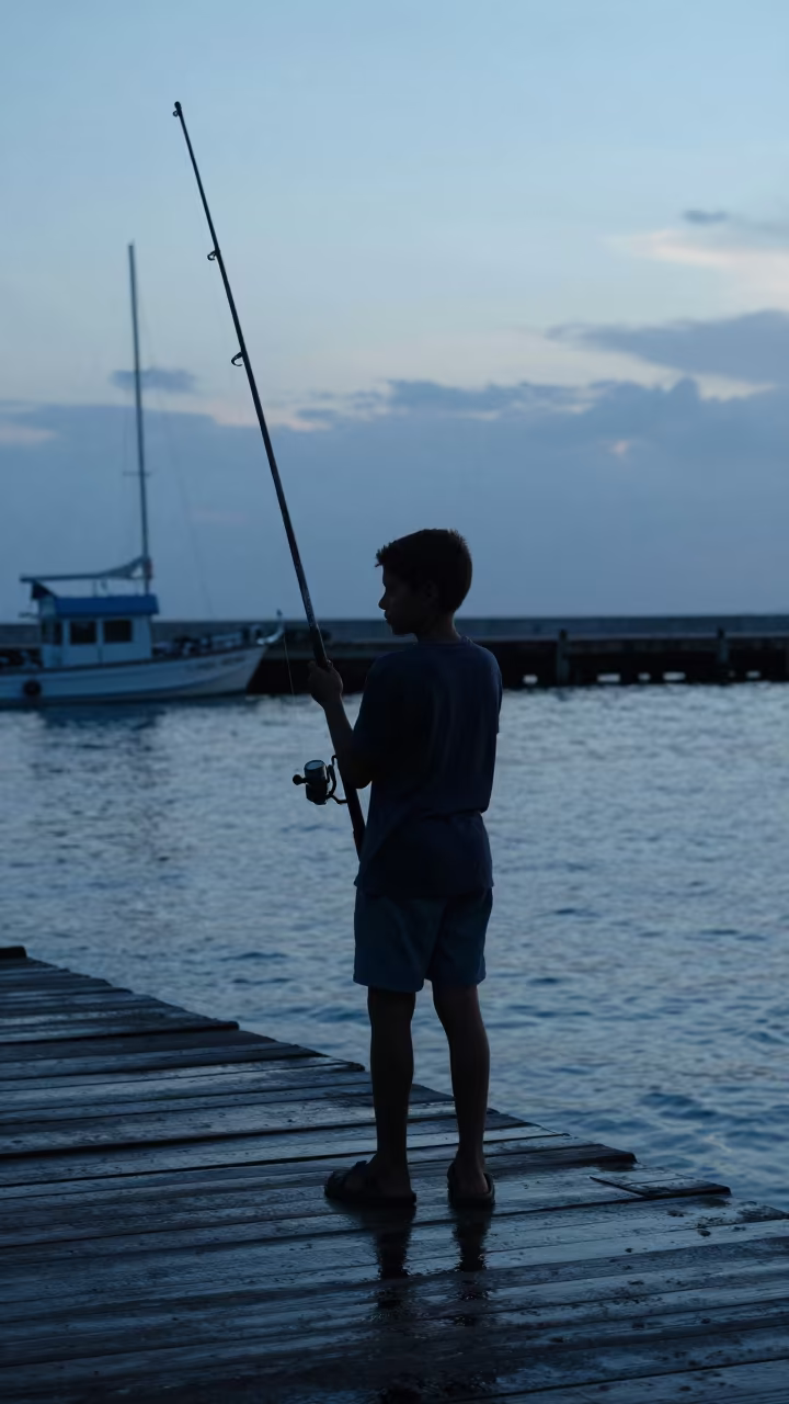 Silhouetted Boy with Oversized Rod at La Romana Dock in at a harbor edge in La Romana