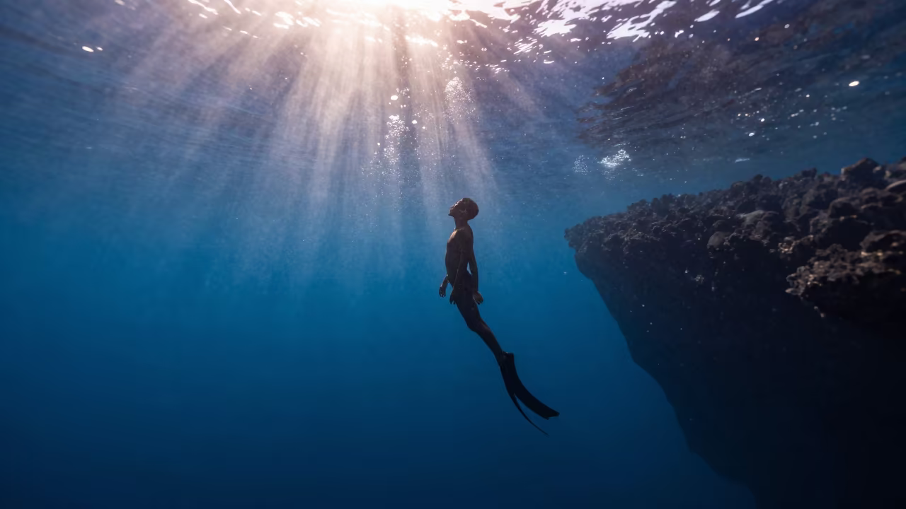 Silhouetted Freediver in Fiji Blue Hole Twilight in beside a volcanic drop-off in Fiji