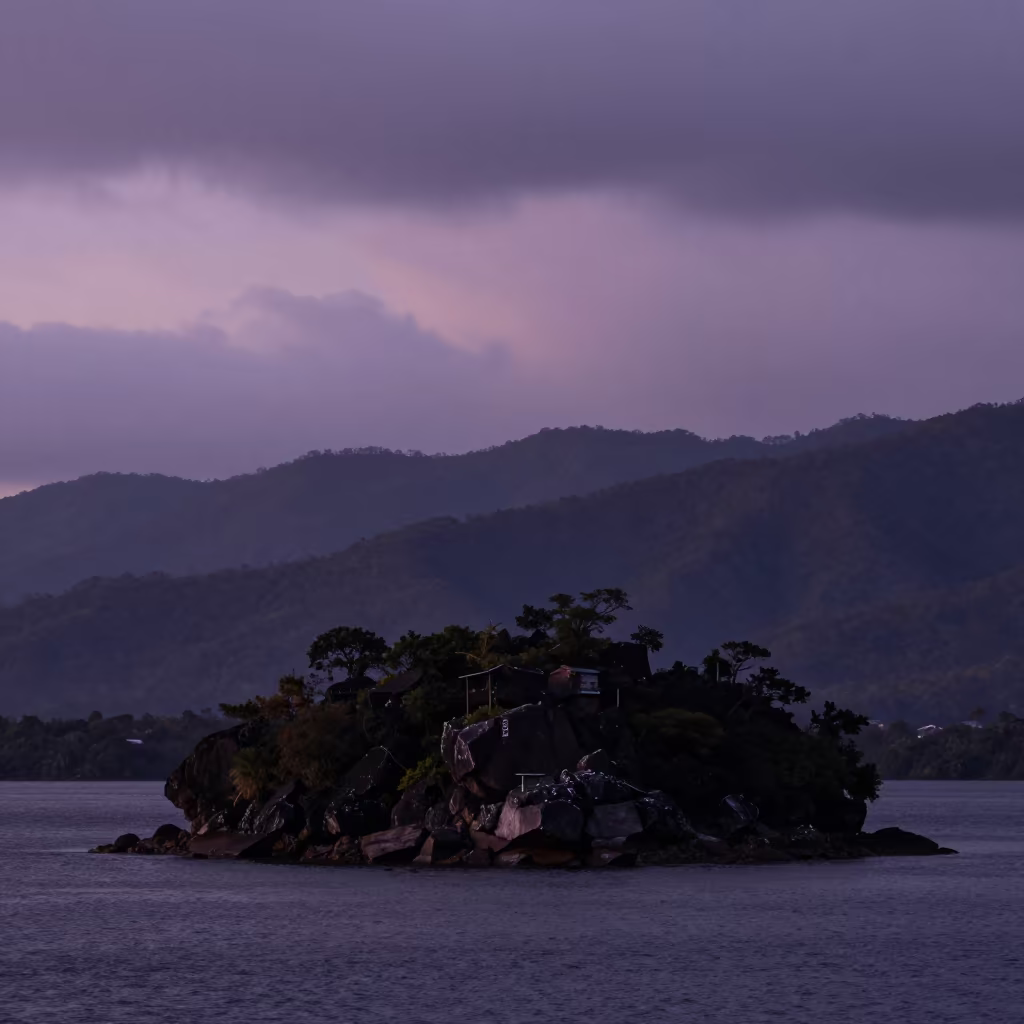 Silhouetted Tombolo Connecting Island to Honduras Ridge in from a ridge above layered foothills in Honduras