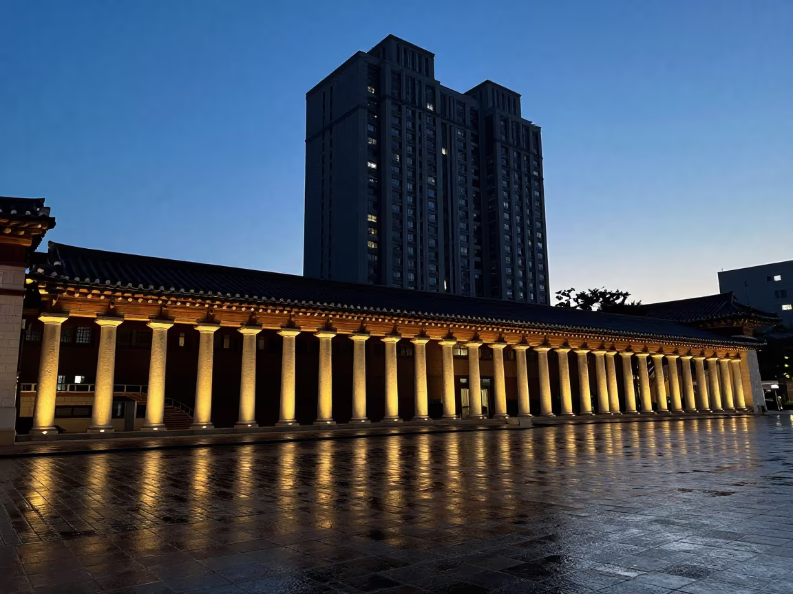 Silhouetted Tower Block Reflecting on Wet Cobblestones in along a colonnaded facade in South Korea