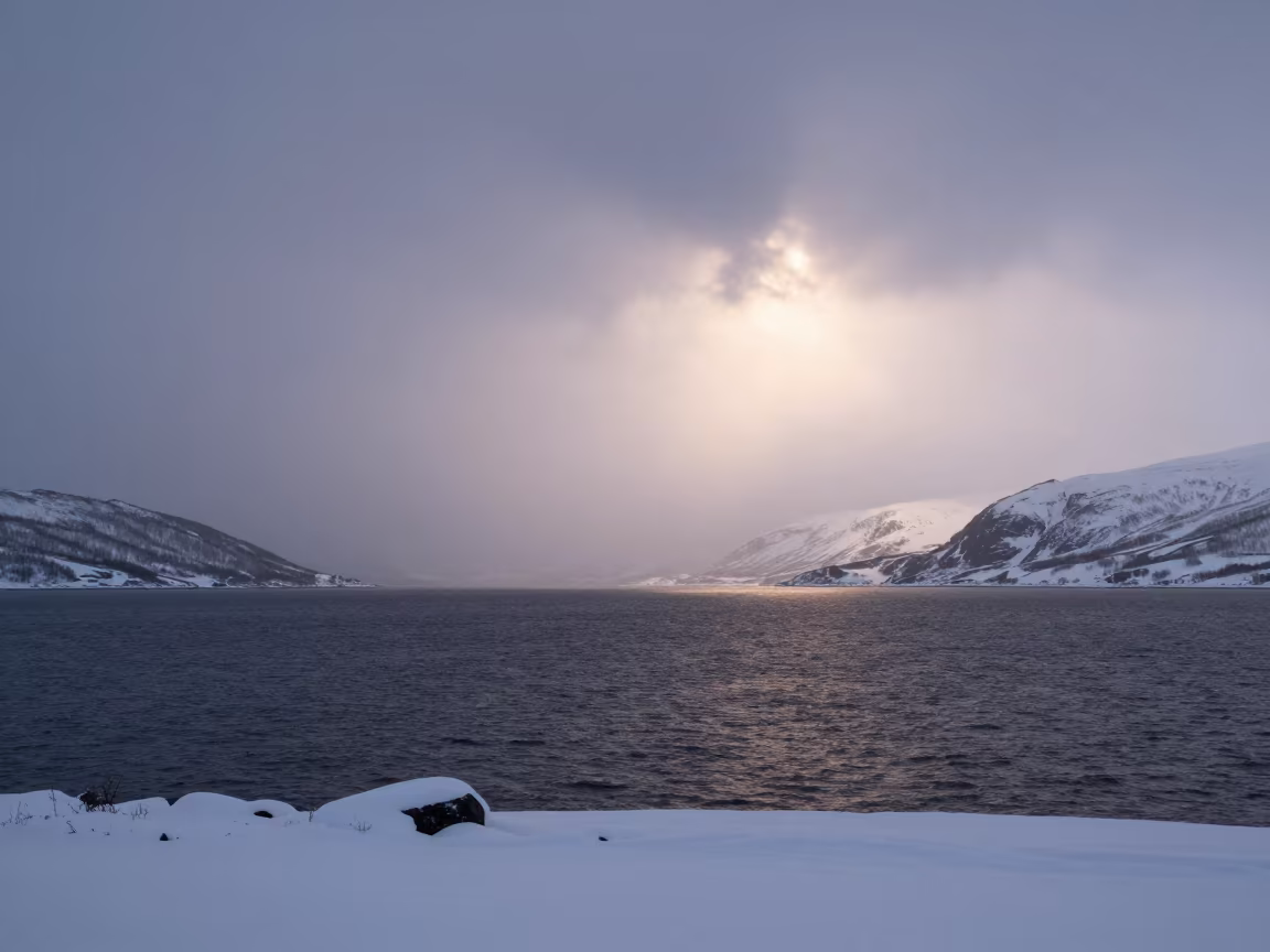 Snow Squall Crossing Norwegian Lake at Sunrise in beneath fast-moving cloud bands in Norway