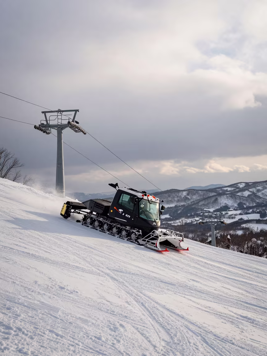 Snowcat Grooming Slope at Dawn Near Sapporo in beside a lift tower above corduroy snow near Sapporo