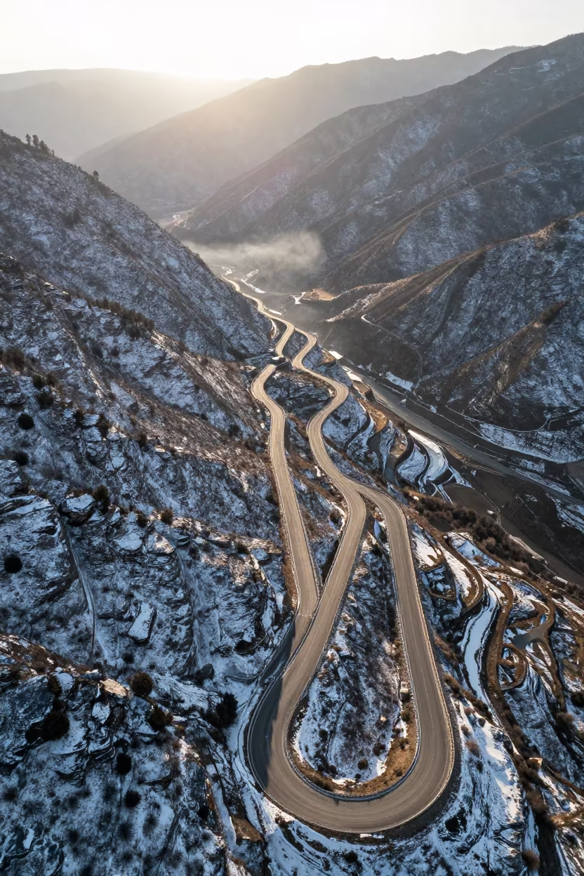 Snowy Mountain Pass Road Zigzag at Golden Hour in at a rocky saddle overlooking a mountain valley near Thimphu