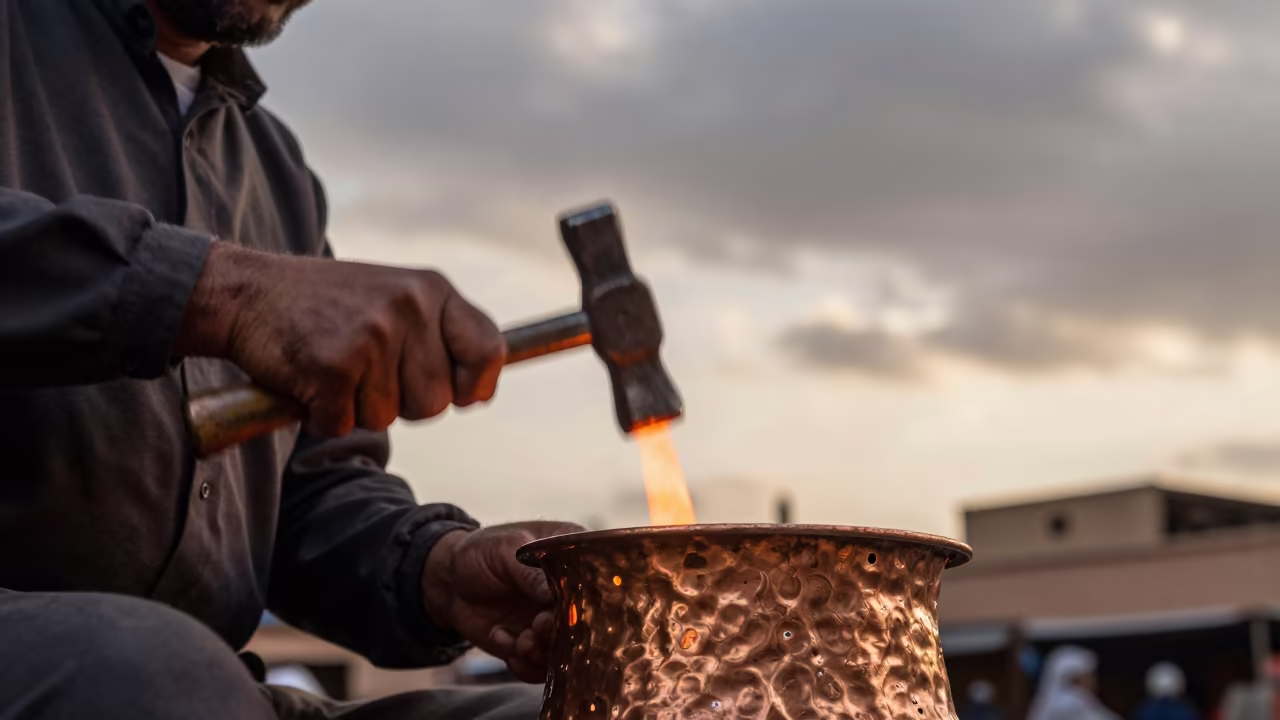 Souk Vendor Hammering Copper Tray Golden Hour in at a textile trader's stall in Gueliz, Marrakech