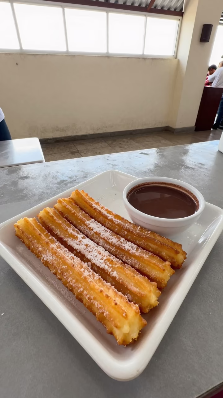 Fresh Spanish Churros with Hot Chocolate at Lobito Market in at a market stall counter in Lobito