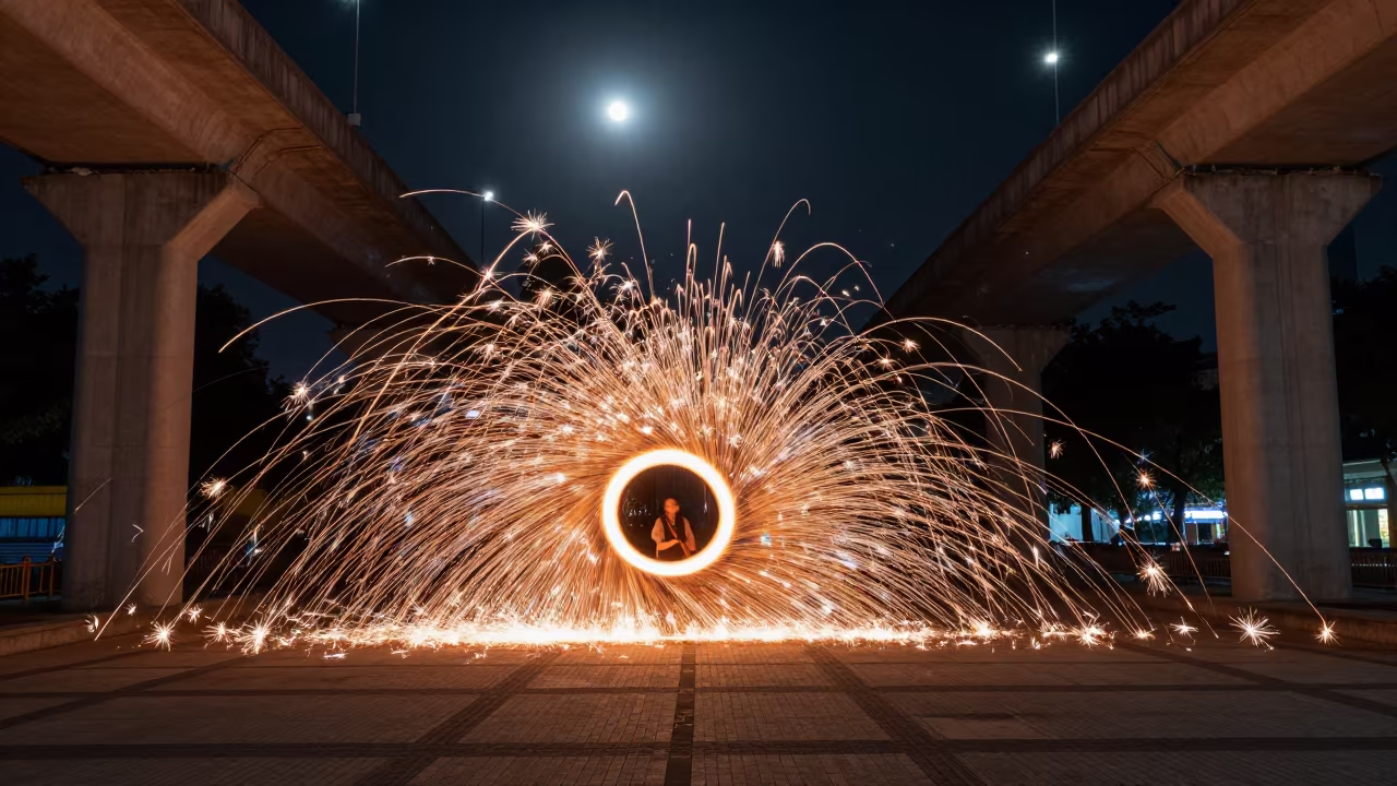 Spinning Steel Wool Sparks Under Macau Bridge Night in across a formal civic plaza near Macau