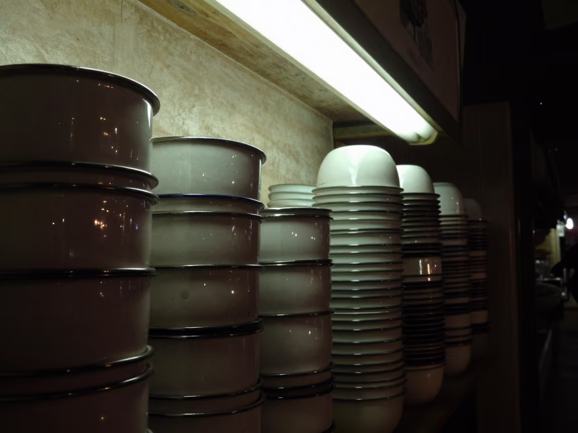 Stacked Enamel Bowls in Fluorescent Light in inside a skylit passageway in Shimla