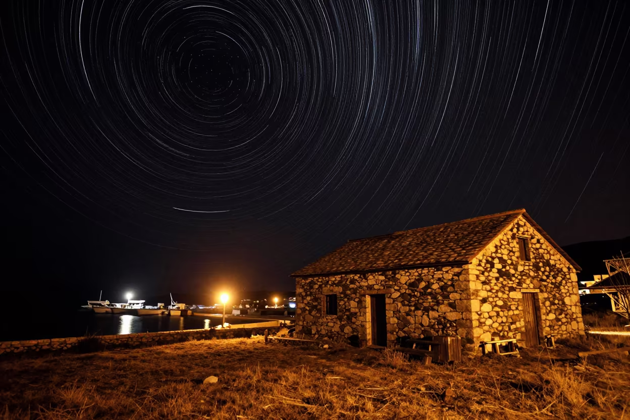 Star Trails Over Stone Barn Near Gjirokaster Harbor in beside a lantern-dotted harbor near Gjirokaster