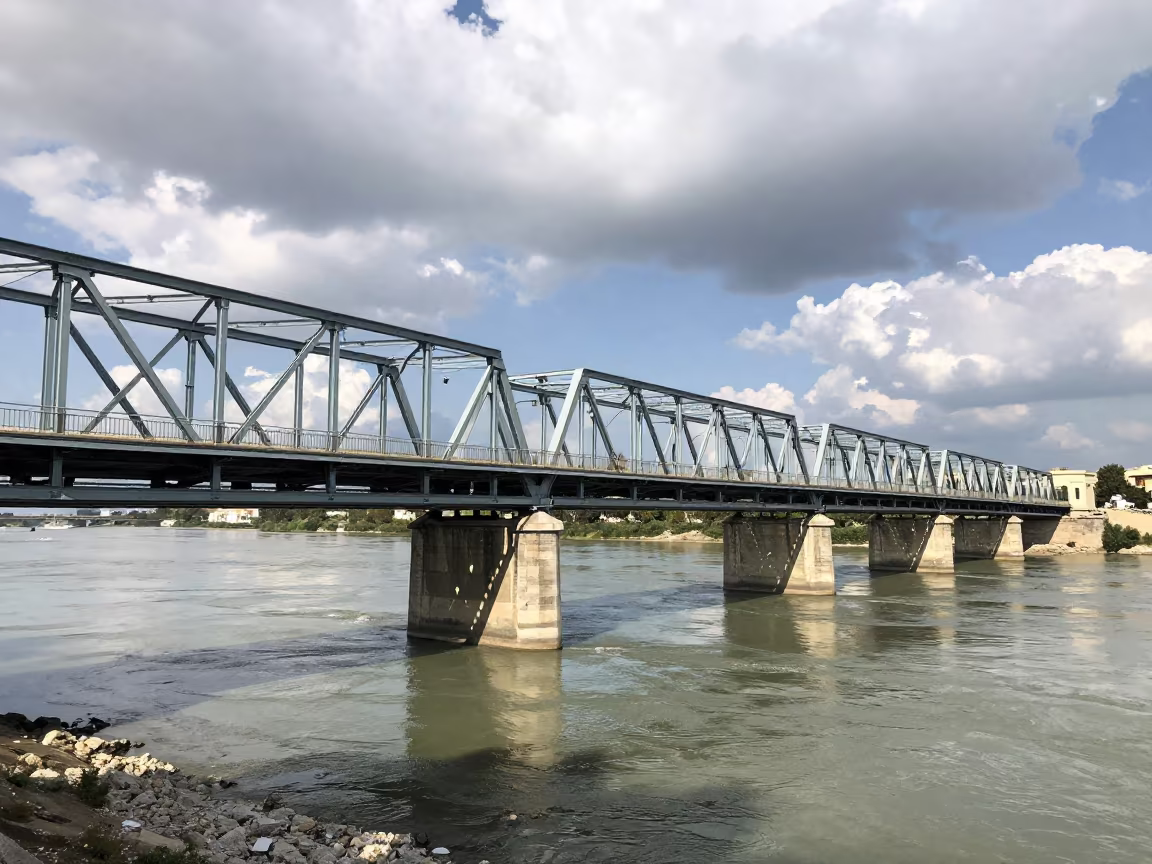 Steel Truss Bridge Casts Shadows on Sicilian River in beside a bridge pier above moving water in Sicily
