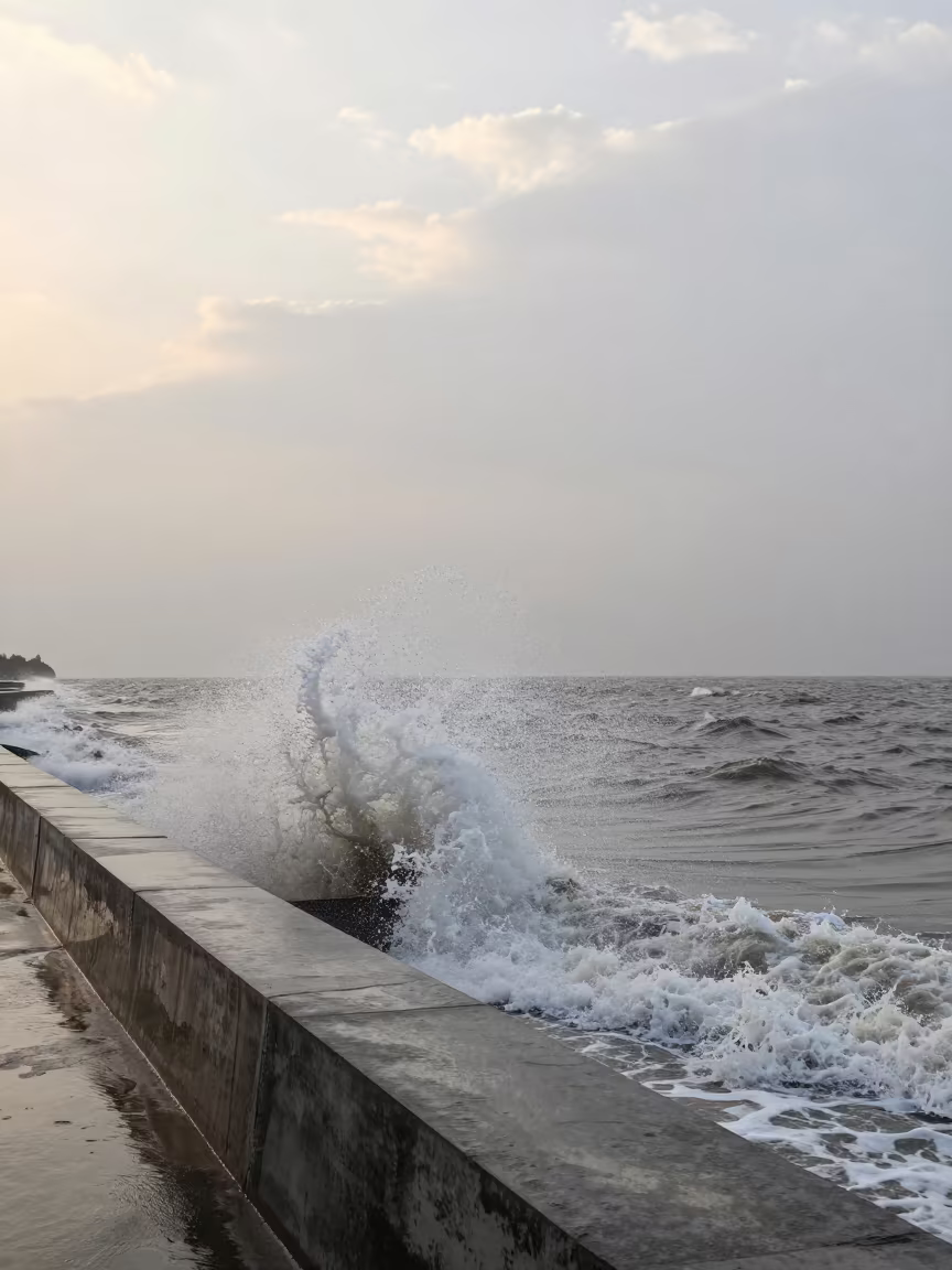 Storm Surge Wave Breaking Over Seawall at Dawn in beneath fast-moving cloud bands in Kashmir