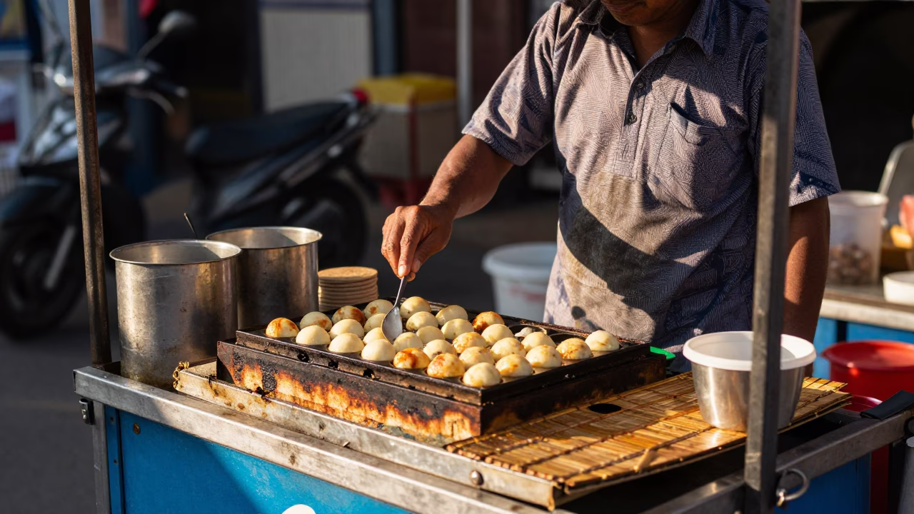 Street Food Vendor Grilling Takoyaki on Bamboo Mat in Kochi India Late Morning in in Kochi, India