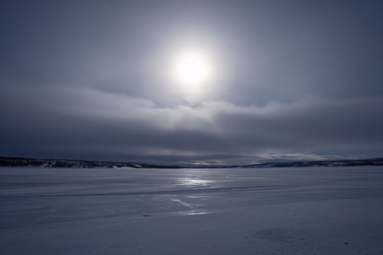 Sun Dog Pair Flanking Sun on Frozen Lake in beneath fast-moving cloud bands in Lapland