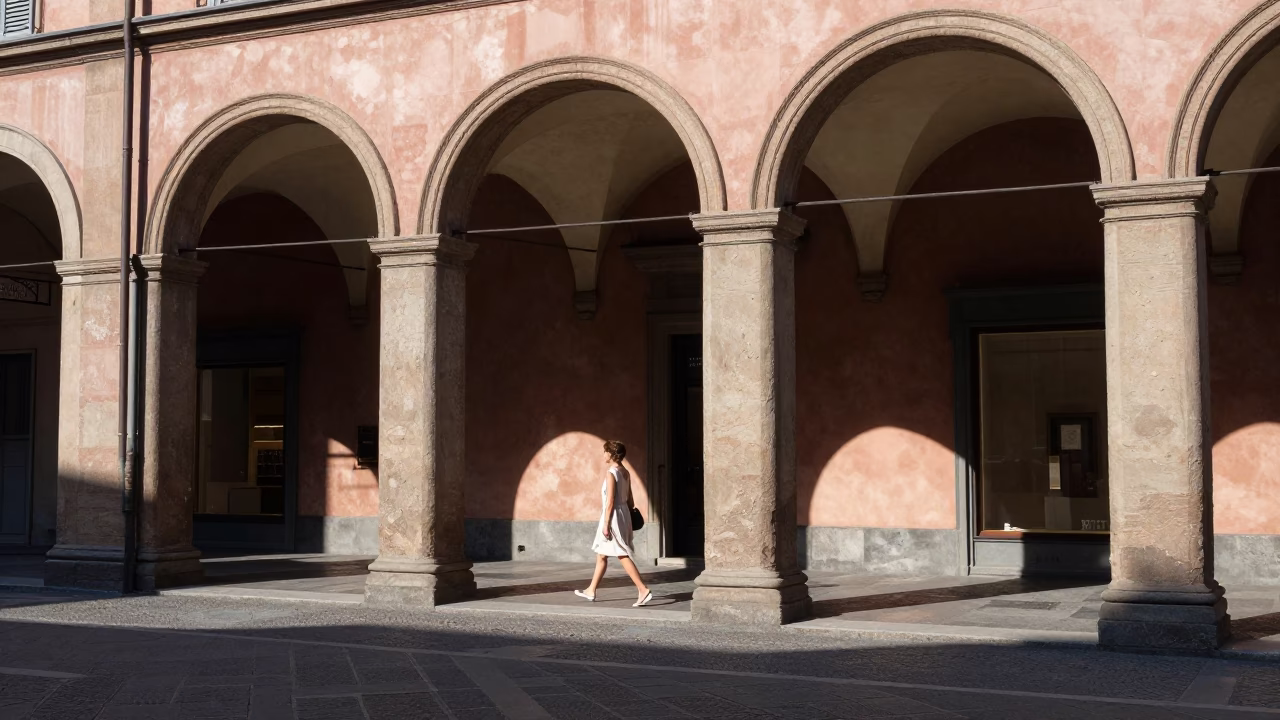 Sunlit Bologna Portico Street Scene with Stone Archways and Casual Pedestrians in in Bologna, Italy
