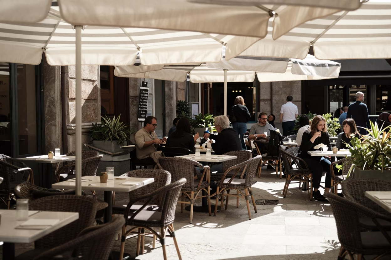 Sunlit Milan Cafe Terrace with Striped Umbrella and Local Diners in Early Afternoon in in Milan, Italy