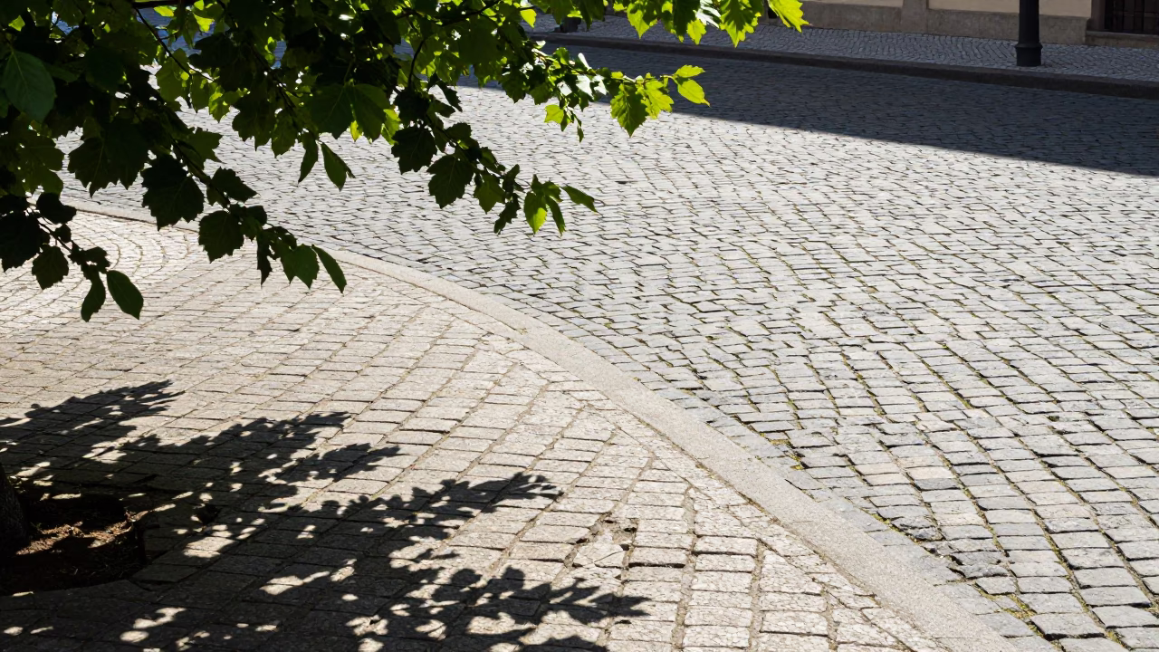 Sunlit Prague Street Corner with Leaf Shadows on Cobblestones and Passing Cyclist in in Prague, Czech Republic