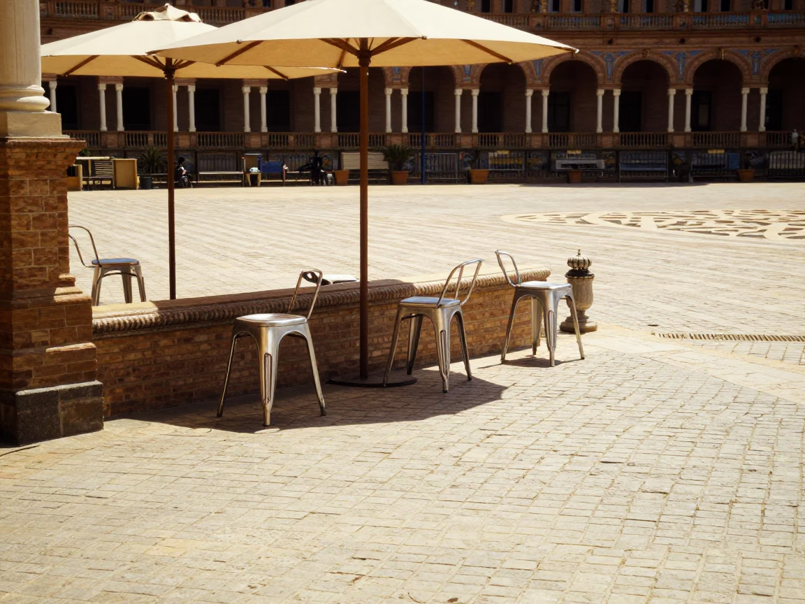 Sunlit Seville Plaza with Metal Stools and Umbrellas at Midday in in Seville, Spain