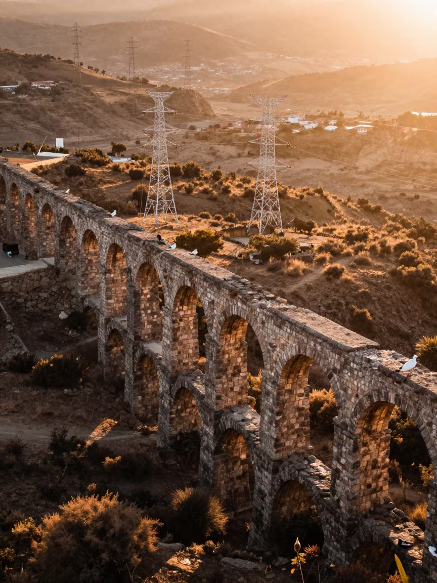 Sunset Over Crumbling Aqueduct Arches in Dry Valley in beneath transmission towers near Medellín