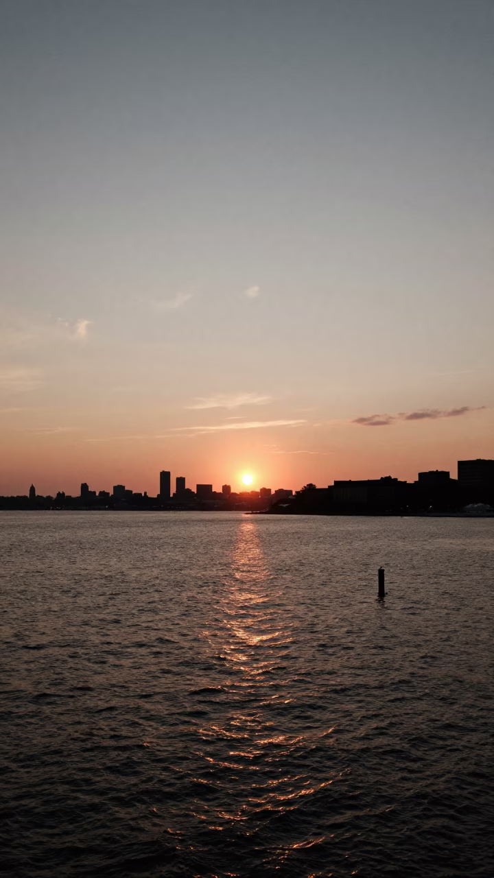 Sunset Over Boston Harbor Waterfront with Distant Skyline and Urban Reflections in in Boston, Massachusetts, United States