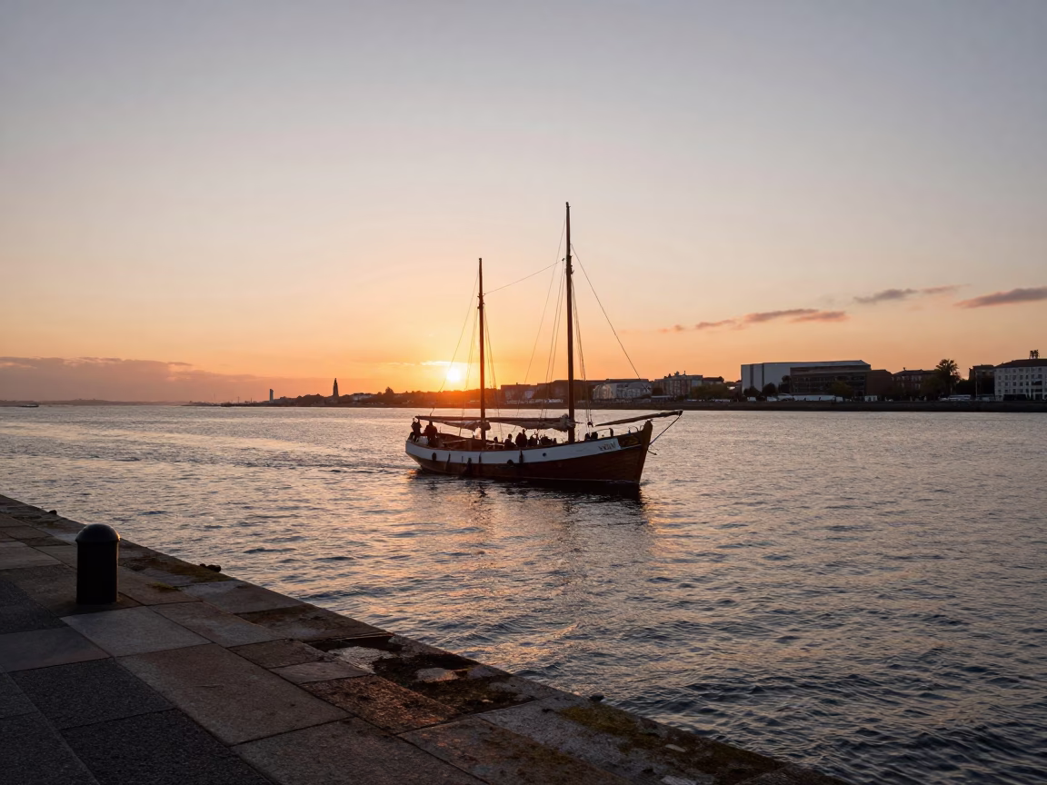 Sunset over Dublin Bay showing traditional sailing vessel and historic stone quay in in Dublin, Ireland