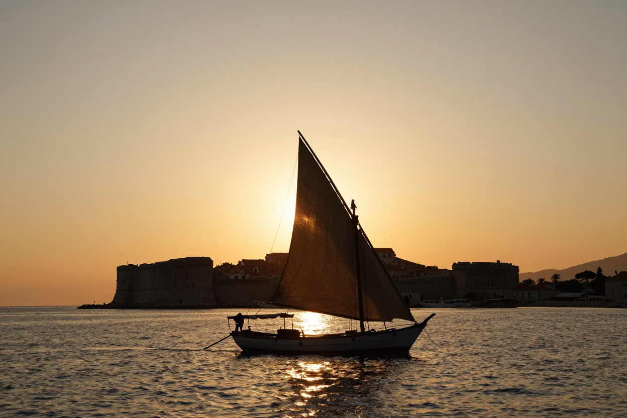 Sunset Silhouette of Traditional Dhow Sailboat Against Dubrovnik Old City Stone Walls in in Dubrovnik, Croatia