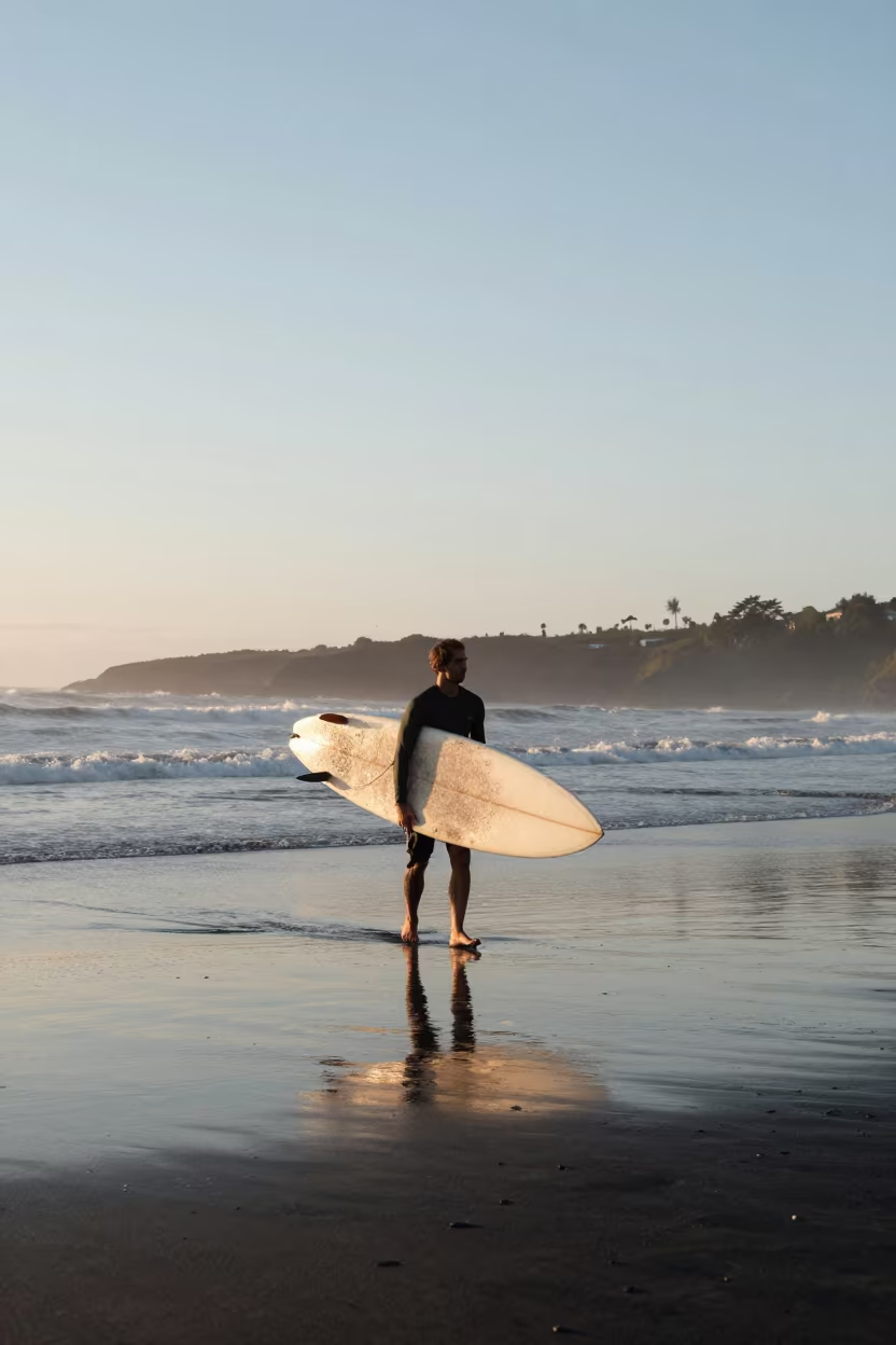 Surfer Carries Longboard on Volcanic Sand in in Colombia
