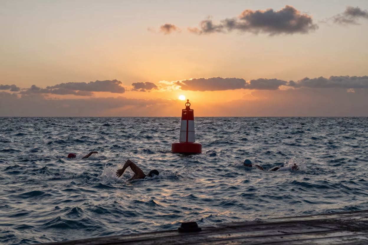 Swimmer navigating turn buoy at Udu harbor sunset in at a harbor quay near Udu