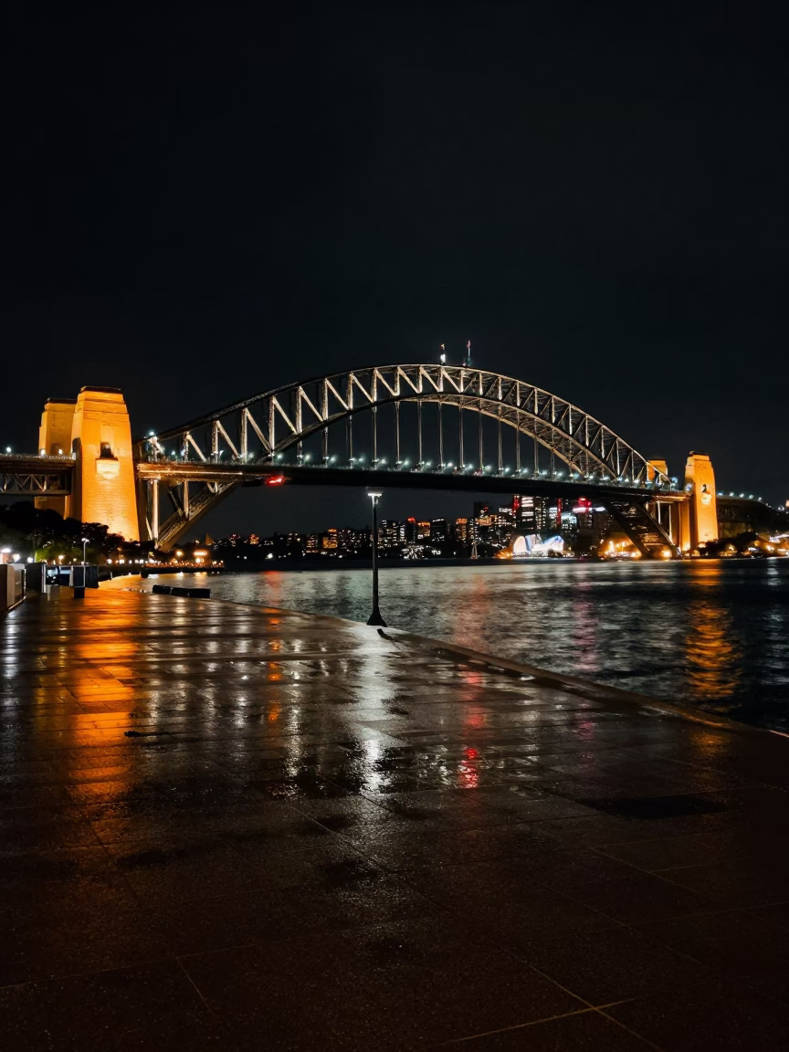 Sydney Harbour Bridge night lights reflecting on wet pavement with city skyline backdrop in in Sydney, New South Wales, Australia