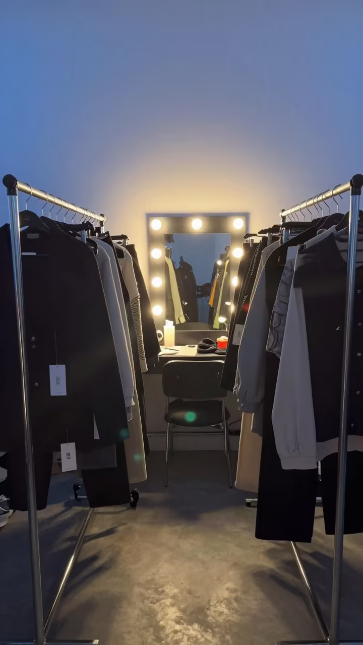 Symmetrical Backstage Rail of Tagged Garments in beside a mirror lined with makeup bulbs near Taiyuan