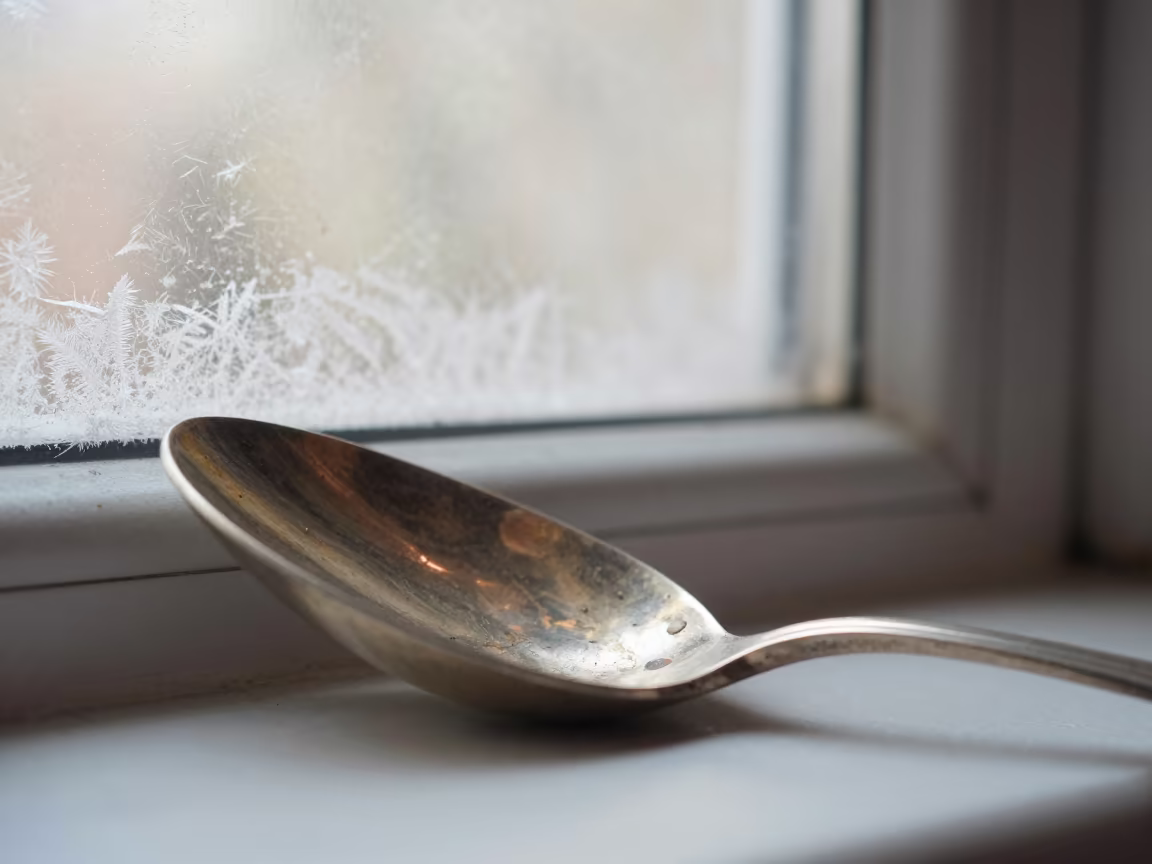 Tarnish Patterns on Antique Silver Spoon in along a frost-edged windowpane in Bhiwandi