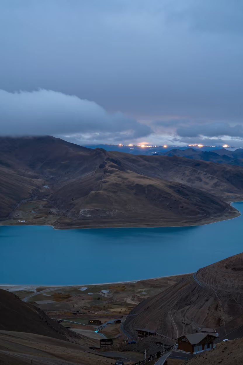 Tibetan Caldera Lake in Blue Evening Light in from a ridge above layered foothills in Tibet