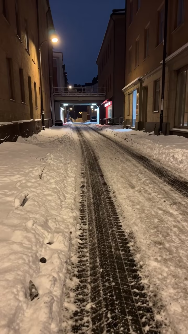 Tire Tracks Through Fresh Snow in Stockholm Alley in beneath a flickering underpass light in Norrmalm, Stockholm