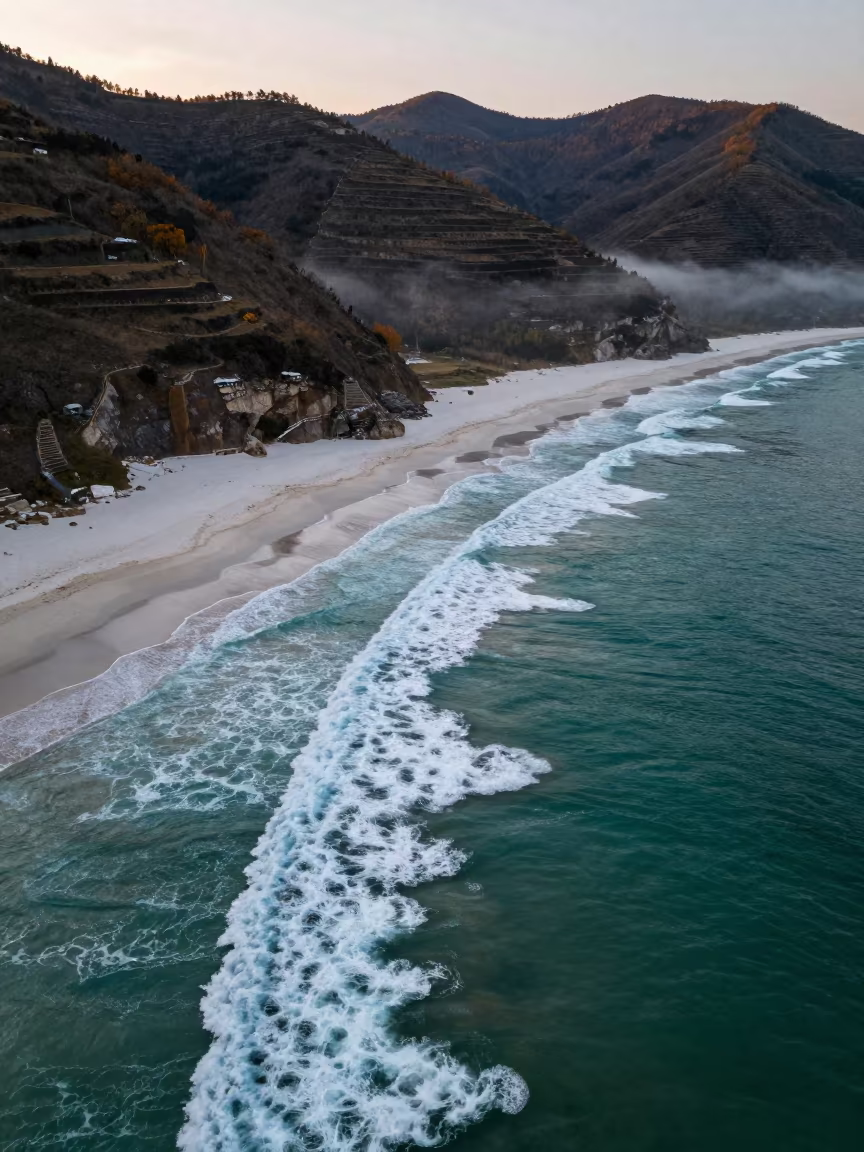 Turquoise Waves Breaking on White Sand at Dusk in far above terraced hillsides near Dubai