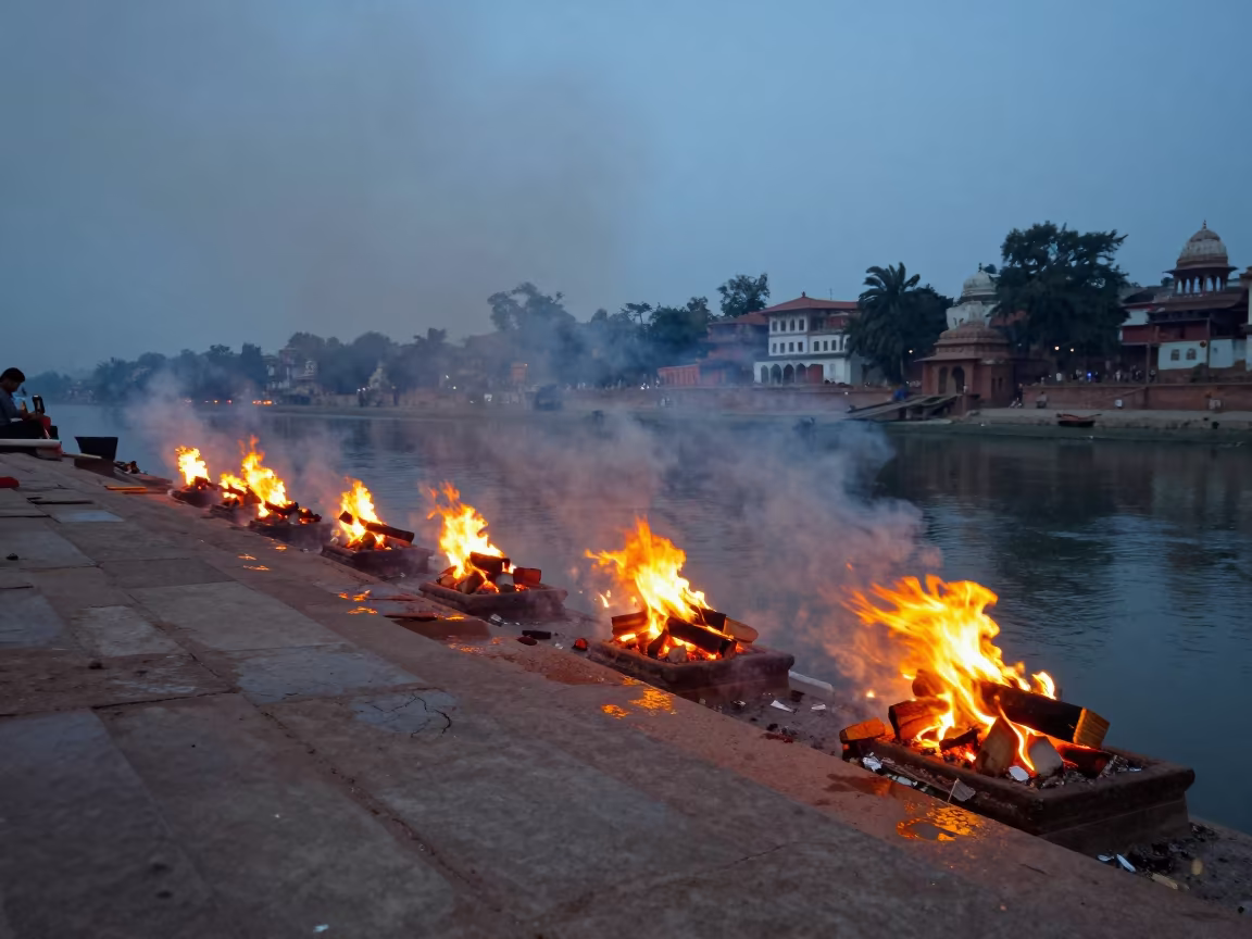 Twilight Smoke Rises Over Sacred Indian Ghat Pyre in at the edge of a sacred pool in India