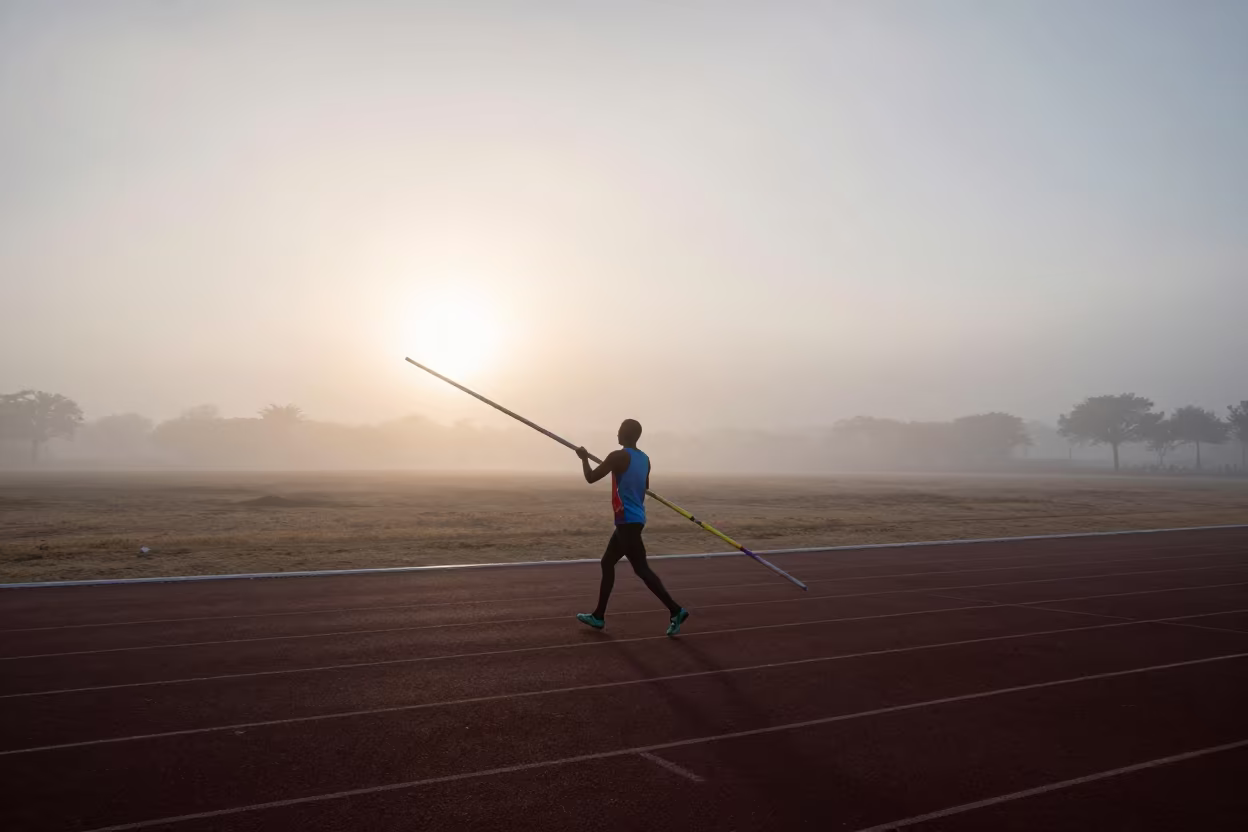 Vaulter Carries Poles Through Dawn Fog on Track in near open fields near Okene
