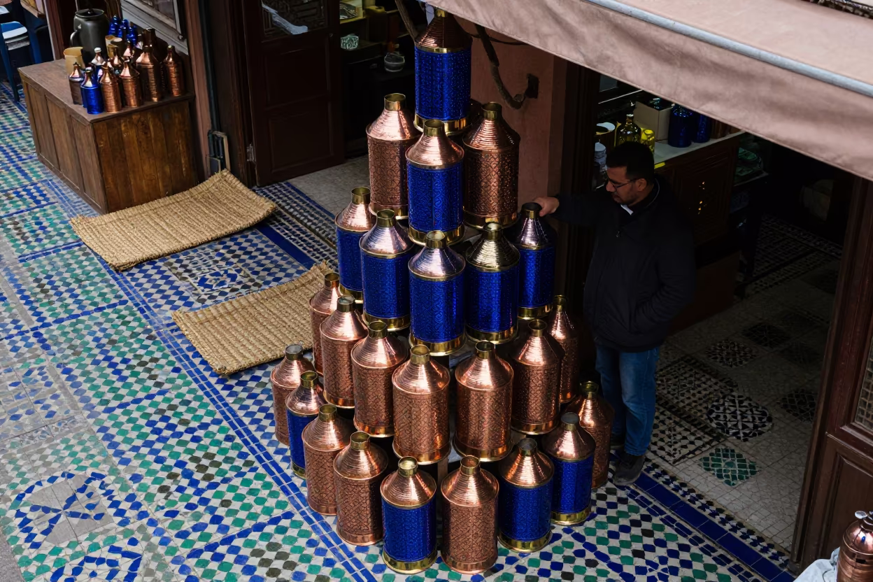 Vendor Stacking Tin Lanterns in Marrakech Souk in in a covered bazaar aisle in Souks, Marrakech