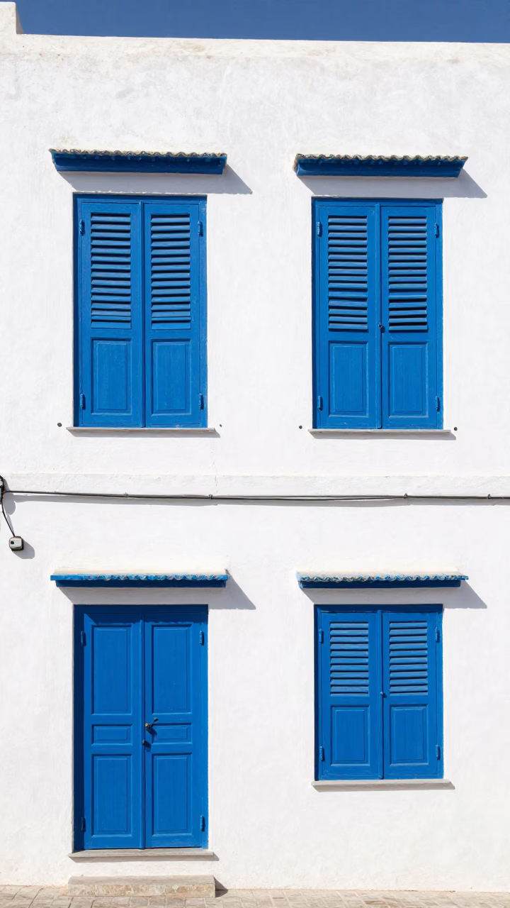 Vibrant Blue Wooden Shutters and White Walls in Historic Essaouira Morocco Under Noon Sun in in Essaouira, Morocco