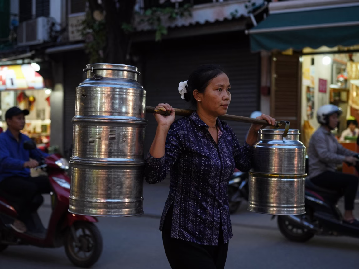 Vietnamese Woman Carrying Bamboo Tiffin Tin in Hanoi in in Hanoi, Vietnam